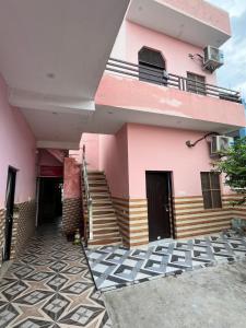 a pink building with stairs and a balcony at Hotel Lotus in Banbāsa