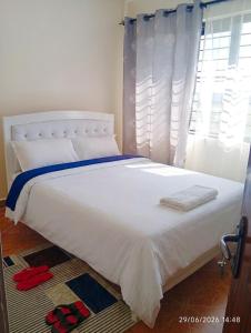 a bedroom with a white bed with a window at EMIC Suites in Nyahururu