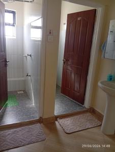 a bathroom with a shower and a toilet and a door at EMIC Suites in Nyahururu +7 photos