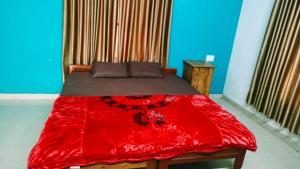 a bed with a red blanket on top of it at Sivadurga in Varkala