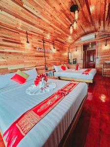 three beds in a room with wooden walls at Keereethara chiewlarn in Ban Bang Kaeo