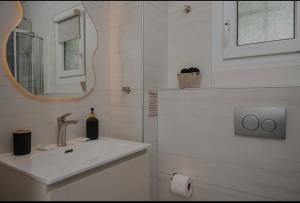 a white bathroom with a sink and a mirror at Dimitra Suites in Pythagoreio