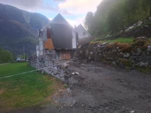 a house on the side of a hill with a stone wall at Jordamorstova in Aurland +24 photos
