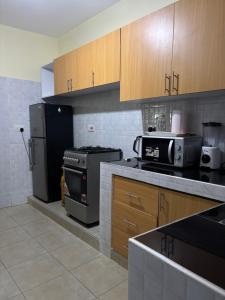 a kitchen with black appliances and wooden cabinets at Nesty Homes in Gitura