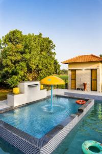 a swimming pool with an umbrella and a house at Gir Vintage Villa in Sasan Gir