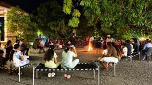 a group of people sitting on benches in front of a fire at Gir Vintage Villa in Sasan Gir
