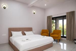 a bedroom with a large white bed and two chairs at Gir Vintage Villa in Sasan Gir