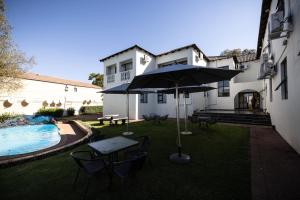 a patio with a table and an umbrella next to a pool at Ecotel Southgate in Southgate
