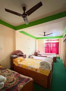 ein Zimmer mit drei Betten und einem Deckenventilator in der Unterkunft Kasturi Hotel in Champapur