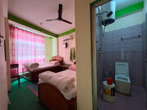 ein kleines Zimmer mit zwei Betten und einer Dusche in der Unterkunft Kasturi Hotel in Champapur