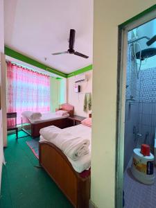 ein Krankenzimmer mit zwei Betten und einer Dusche in der Unterkunft Kasturi Hotel in Champapur