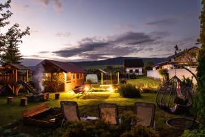 a yard with chairs and a playground at sunset at Penzion JAS in Zuberec