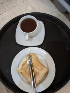 a plate with a piece of toast and a cup of coffee at Legenda Beril Hostel in Makassar