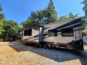 an rv parked on the gravel next to trees at Gold Rush Historical Resort in Sonora