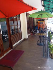 a patio with a table and a red and green umbrella at Legenda Beril Hostel in Makassar