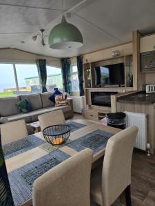 a living room with a dining room table with chairs at Bayview at Pengarreg in Llanrhystyd