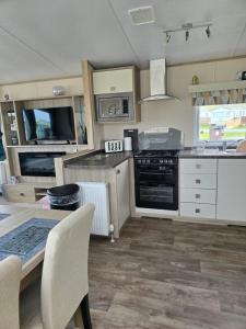 a kitchen with a table and a stove top oven at Bayview at Pengarreg in Llanrhystyd