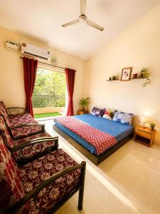 a bedroom with a bed and a chair and a window at Harmony Vista in Calangute