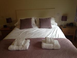 a bedroom with a bed with two towels on it at Manor Garden Lodge in Wirral
