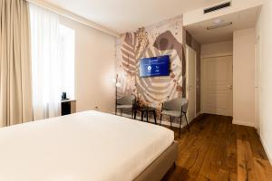 ein Schlafzimmer mit einem Bett und einem Fernseher an der Wand in der Unterkunft KT exclusive hotel in Cagliari