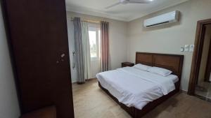 a bedroom with a bed with white sheets and a window at حياة النعيم in Salalah