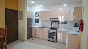 a kitchen with pink cabinets and a stove top oven at حياة النعيم in Salalah