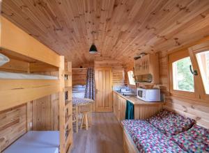 a log cabin with a bed and a kitchen at Camping Onlycamp du Rouergue in Villefranche-de-Rouergue
