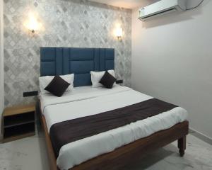 a bed with a blue headboard in a room at Hotel Abhijeet Inn in Raipur