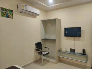 a room with a chair and a tv on the wall at Hotel Abhijeet Inn in Raipur +1 photo