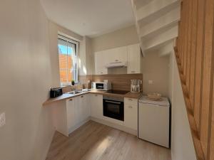a small kitchen with white cabinets and a window at Le Petit Bleu - Charming House in Yport