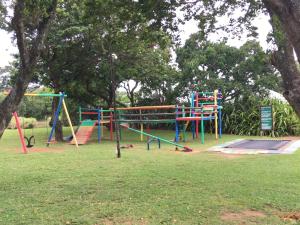 a colorful playground in a park with a tree at Caribbean Estates Villa B10 on Barbados in Port Edward