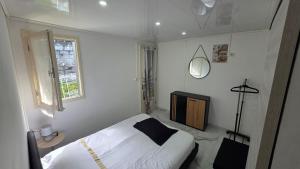 a white bedroom with a bed and a window at Entre Mer et Volcan ,piscine chauffée au tampon in Bel Air