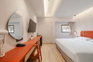 ein Schlafzimmer mit einem Bett und einem Schreibtisch mit Spiegel in der Unterkunft Jace Siam Hotel in Bangkok