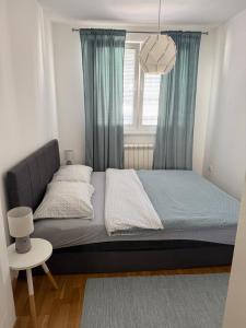 a bedroom with a bed with blue curtains and a window at SK Blue apartment in Lukavica +5 photos