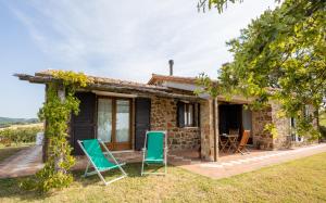 a stone house with two lawn chairs in front of it at La Casina dei Lapi in Catabbio