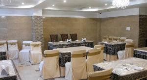 a dining room with tables and chairs and a chandelier at Hotel Rio Haridwar in Haridwār