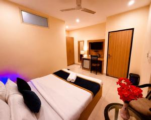 a hotel room with a bed and a table with flowers at Hotel Rio Haridwar in Haridwār