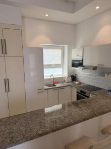 a kitchen with white cabinets and a granite counter top at Hawana Studio SL-3 in Wādī Khasbar +4 photos