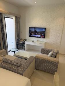 a living room with two couches and a tv on a wall at Hawana Studio SL-3 in Wādī Khasbar