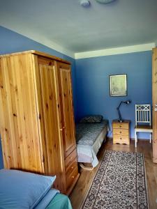 a bedroom with blue walls and a bed and a cabinet at Vormsi Ohvitseride Maja korter nr 2 in Hullo