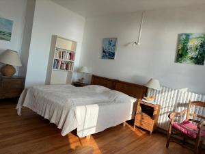 a bedroom with a bed and a chair and a book shelf at FACE A LA MER , L ARTISTE in Ambleteuse