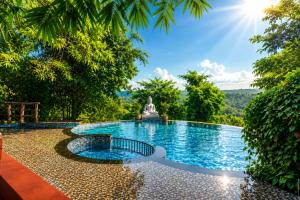 a pool in the middle of a garden with a statue at Nature Trails Rock Valley, Goa in Ponda