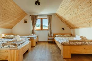 three beds in a room with wooden ceilings at Sokoli Zakątek - domki w Bieszczadach in Bukowiec
