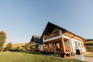 a house with a wrap around porch in a field at Sokoli Zakątek - domki w Bieszczadach in Bukowiec