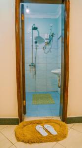 a bathroom with a shower with two shoes on a rug at Neriah Suites in Kabale +29 photos