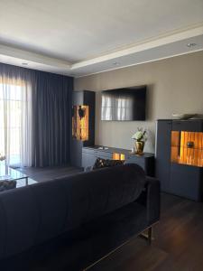 ein Wohnzimmer mit schwarzem Sofa und Fernseher in der Unterkunft Villaggio Hotel in Mackenbach