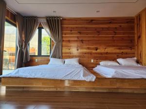 two beds in a bedroom with a wooden wall at Coffee Myhome in Kon Rung (1)