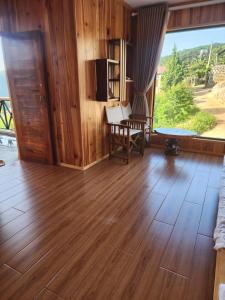 a living room with wooden floors and a large window at Coffee Myhome in Kon Rung (1) +28 photos