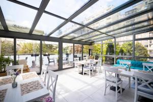 ein Wintergarten mit Tischen, Stühlen und Fenstern in der Unterkunft Hotel Opole Centrum in Oppeln