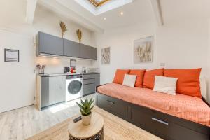 an orange couch in a room with a kitchen at Bright studio - RER B - Plateau de Saclay in Palaiseau